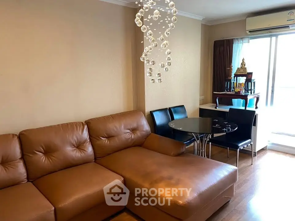 Spacious living room with leather sofa and modern chandelier in a cozy apartment.