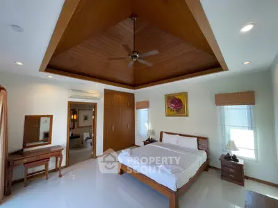 Spacious bedroom with wooden ceiling and modern furnishings in a luxury home.