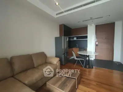 Modern living room with cozy sofa and compact kitchen area in open layout apartment.