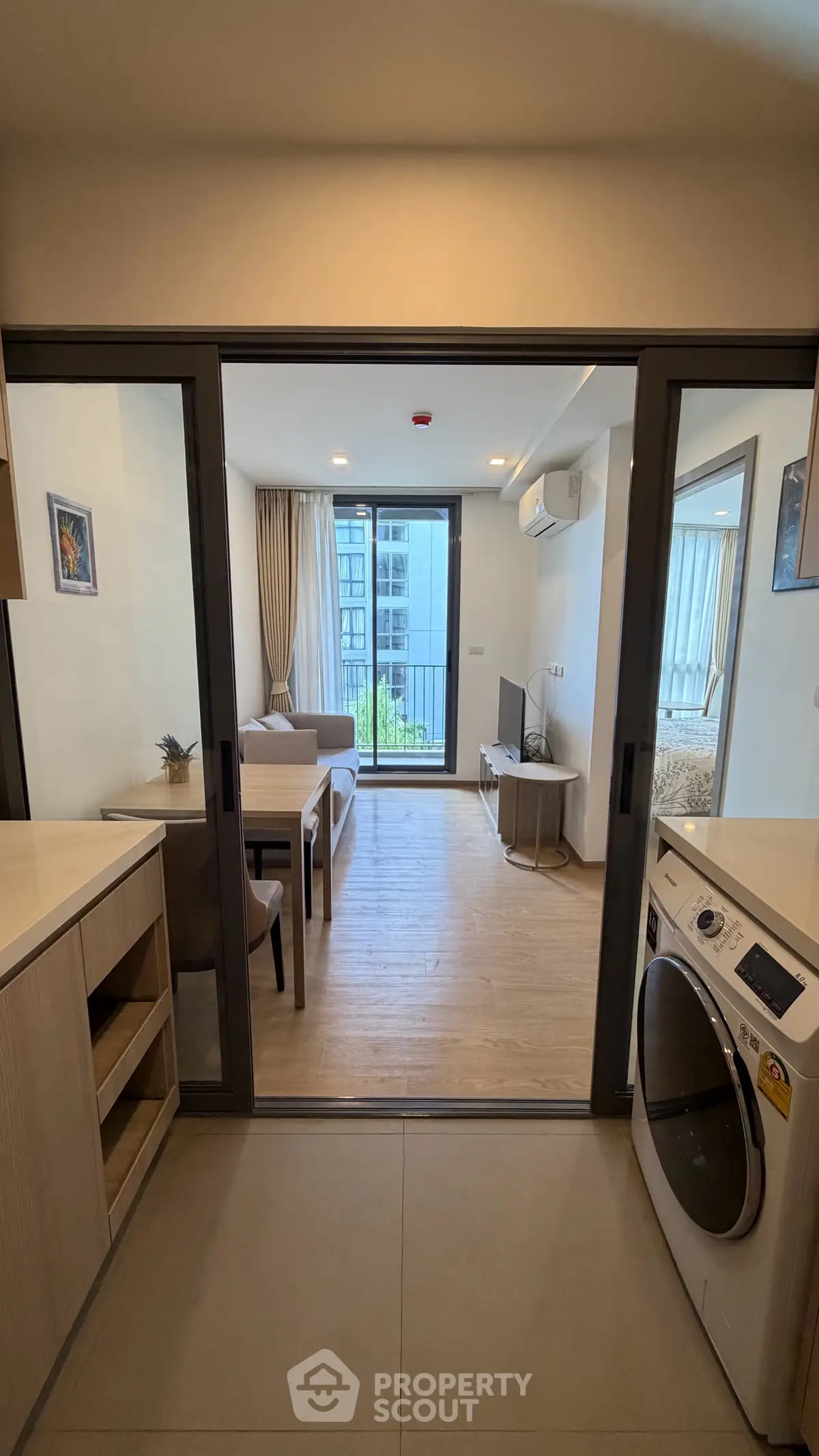 Modern apartment with open layout, featuring a cozy living room and kitchen with a washing machine.