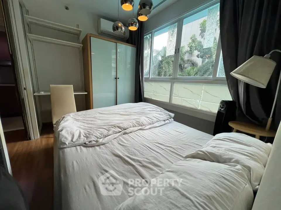 Cozy bedroom with large window and modern lighting in a stylish apartment.