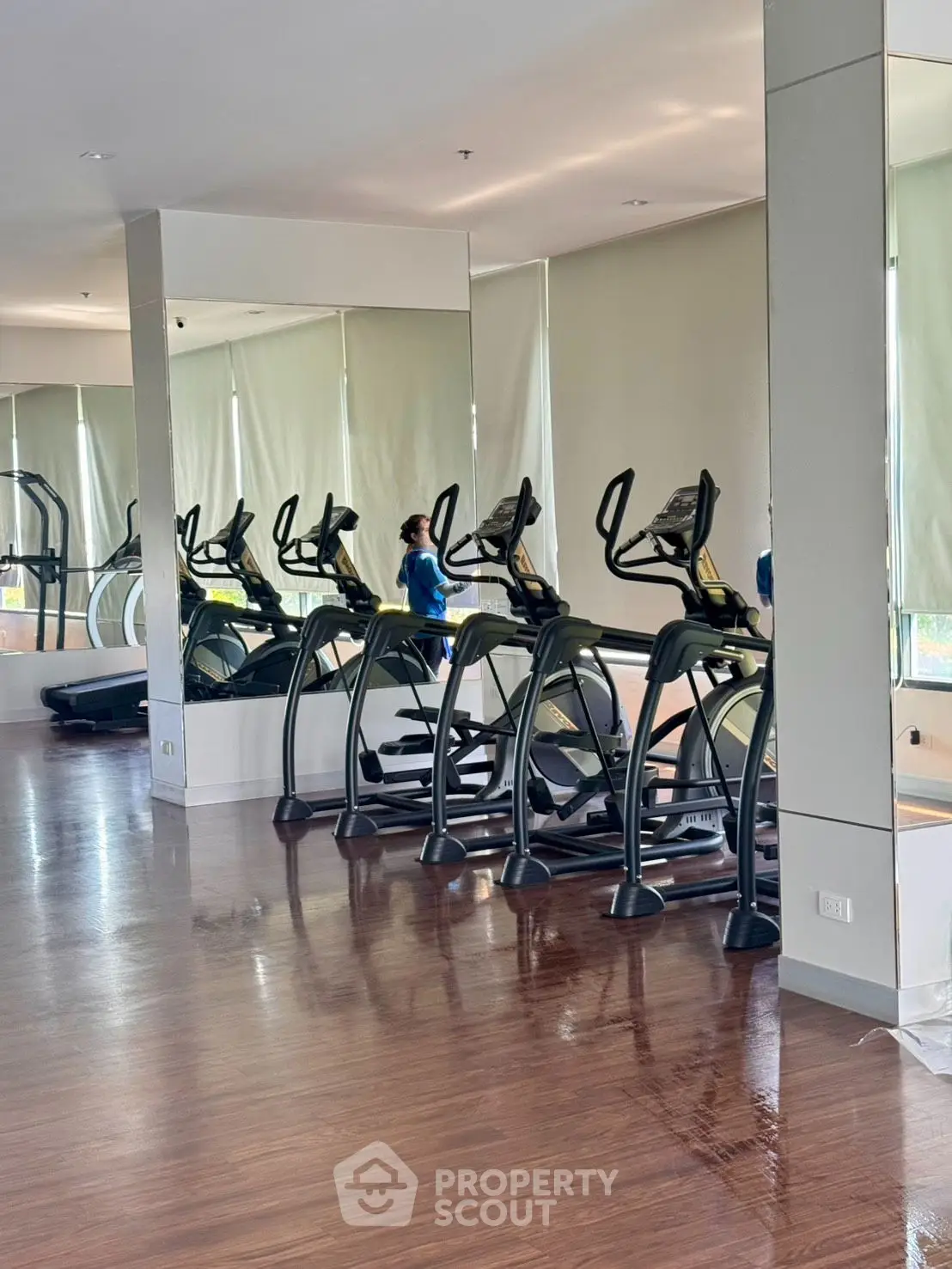 Modern gym with sleek exercise equipment and polished wooden floors in a luxury apartment complex.