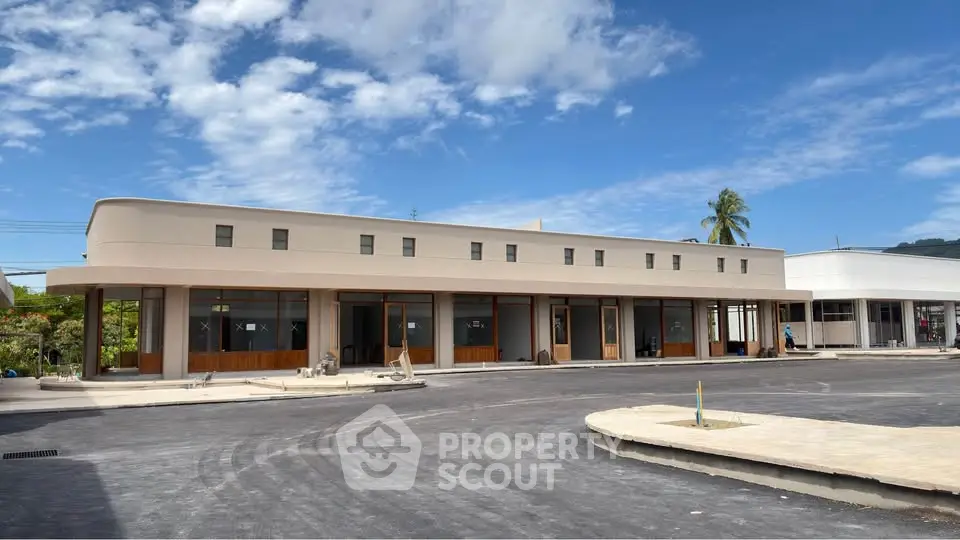 Modern commercial building with sleek design and ample parking space under a clear blue sky.