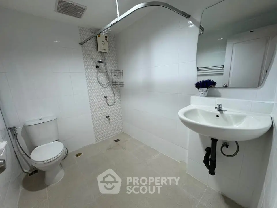 Modern bathroom with white tiles, shower, and sleek fixtures in a contemporary home.