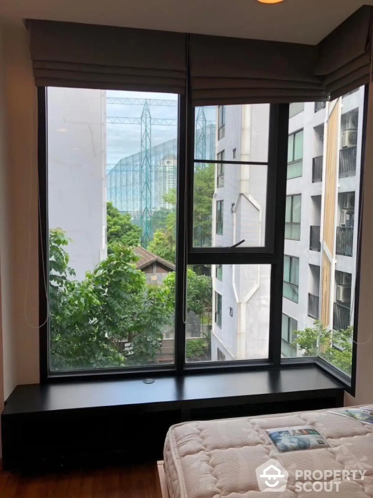 Cozy bedroom with large window offering city view and natural light.