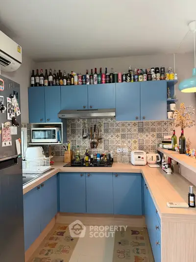 Charming kitchen with blue cabinets and stylish backsplash, featuring modern appliances and cozy decor.