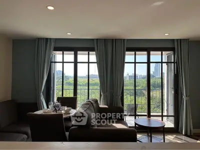 Spacious living room with large windows offering stunning cityscape views and elegant furnishings.