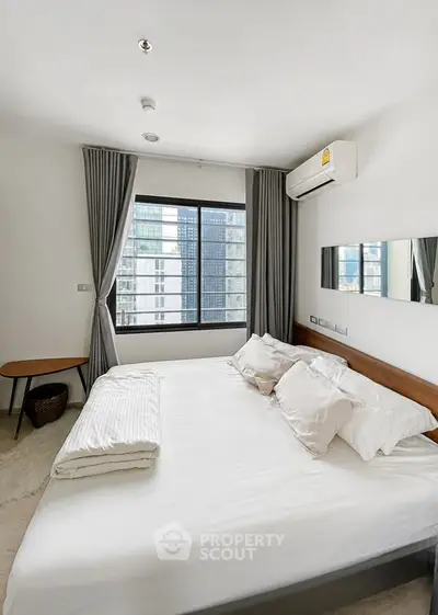 Modern bedroom with large window and city view, featuring a comfortable bed and air conditioning.
