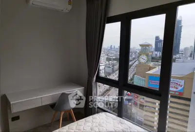Modern bedroom with city view, featuring a sleek desk and large windows for natural light.