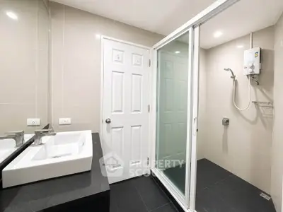 Modern bathroom with sleek design featuring a glass shower enclosure and stylish sink.