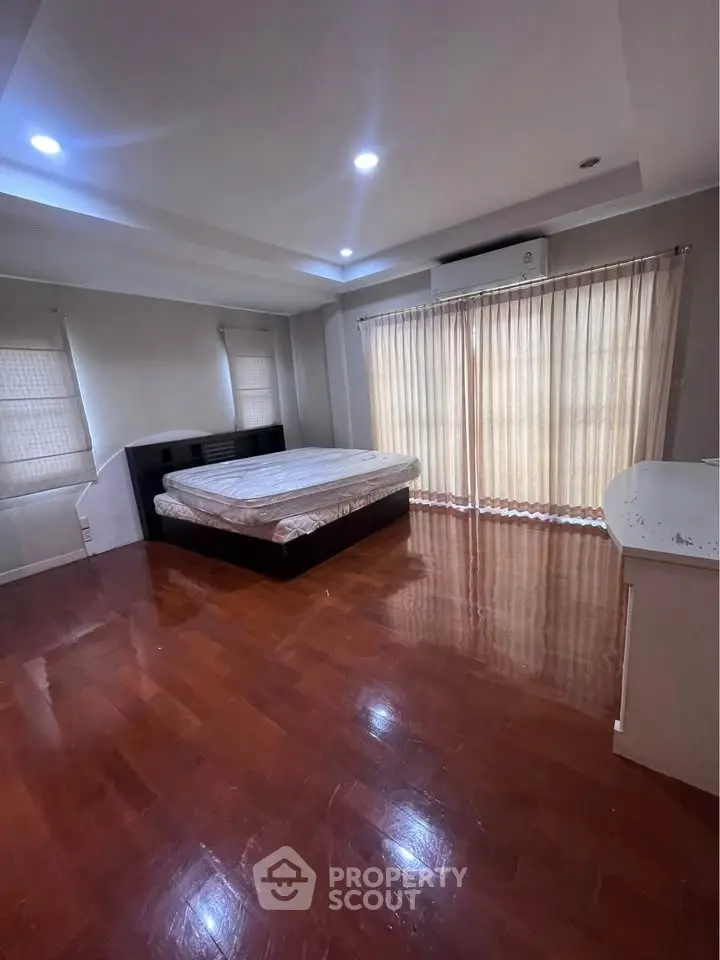 Spacious bedroom with wooden flooring and natural light
