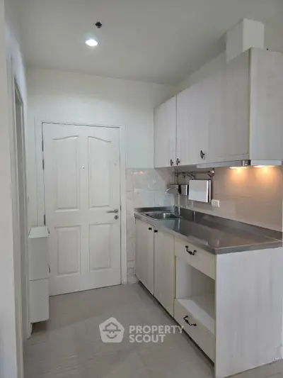 Modern kitchen with sleek cabinetry and stainless steel countertop in a compact layout.