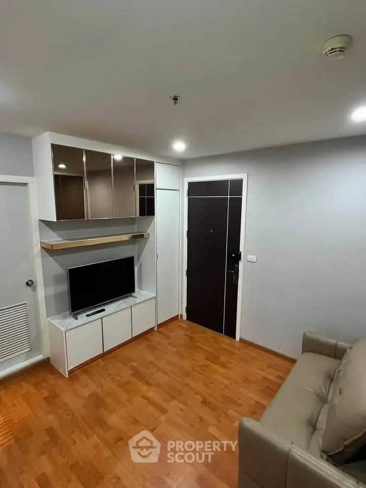 Modern living room with wooden flooring and sleek TV unit in a cozy apartment.