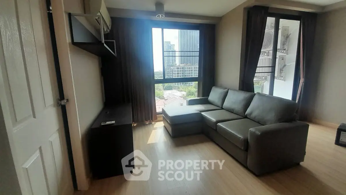 Modern living room with city view, featuring sleek furniture and large windows for natural light.
