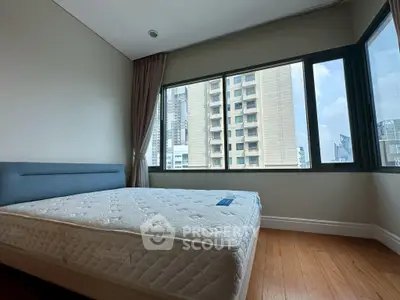 Spacious bedroom with large windows offering city views and natural light.