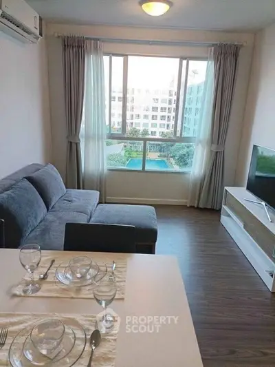 Modern living room with pool view, featuring cozy sofa and elegant dining setup.