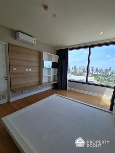 Spacious bedroom with large window offering stunning city view