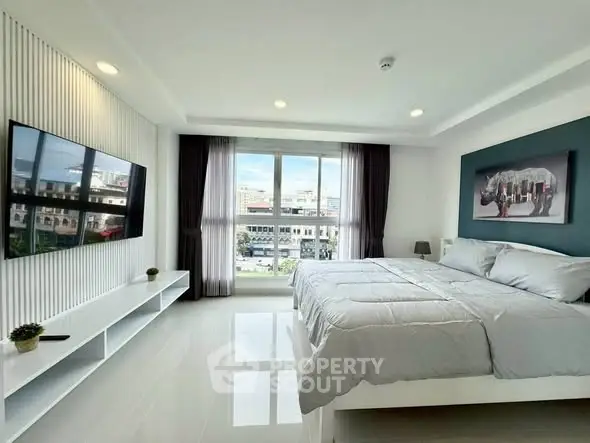 Spacious modern bedroom with large window and city view, featuring sleek decor and wall-mounted TV.
