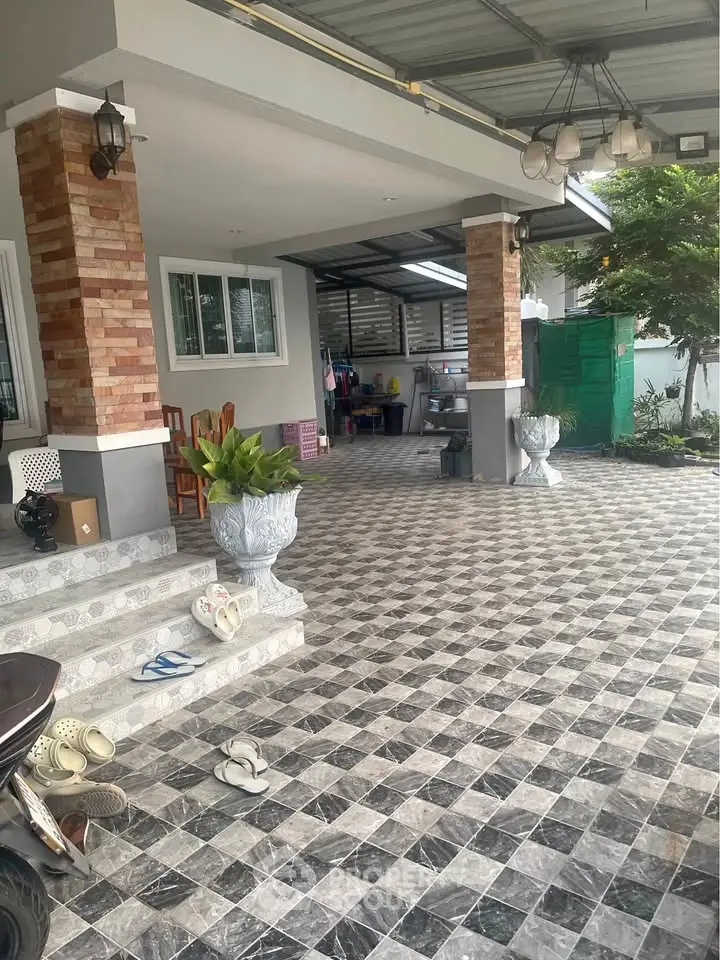 Spacious covered patio with stylish tiled flooring and decorative columns, perfect for outdoor relaxation.