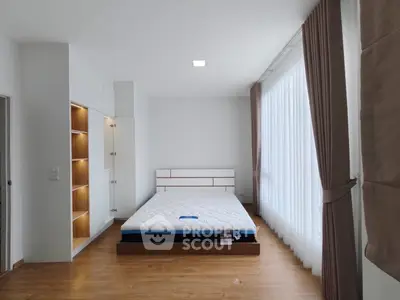 Spacious bedroom with large windows and modern design, featuring a comfortable bed and ample storage.