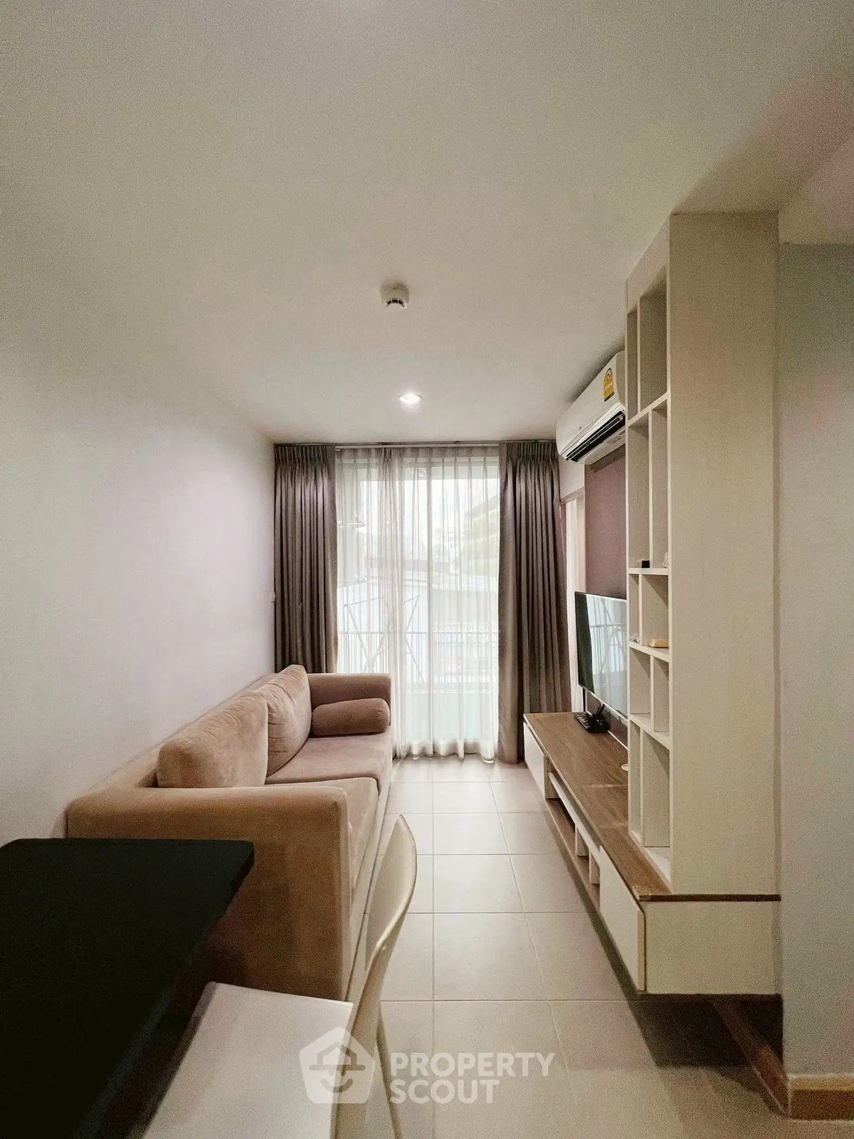 Modern living room with cozy sofa and entertainment center, featuring natural light from large windows.