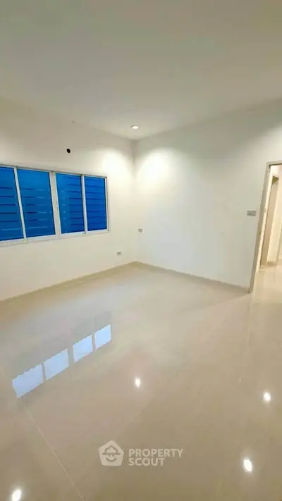 Spacious empty room with large windows and glossy tiled floor, perfect for customization.