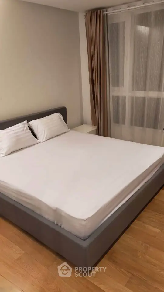 Spacious bedroom with modern decor and large window for natural light.