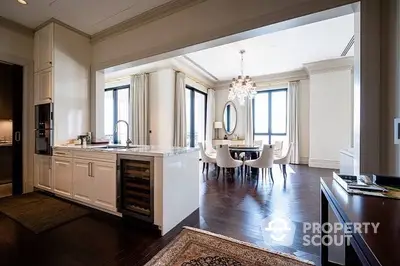 Elegant open-plan living space with a modern kitchen and a sophisticated dining area, featuring rich hardwood floors and classic white cabinetry.