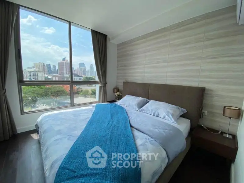 Modern bedroom with large window offering stunning city view