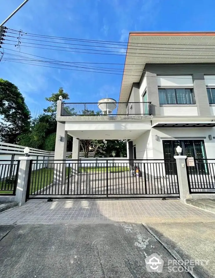 Modern two-story house with spacious balcony and gated driveway in a serene neighborhood.