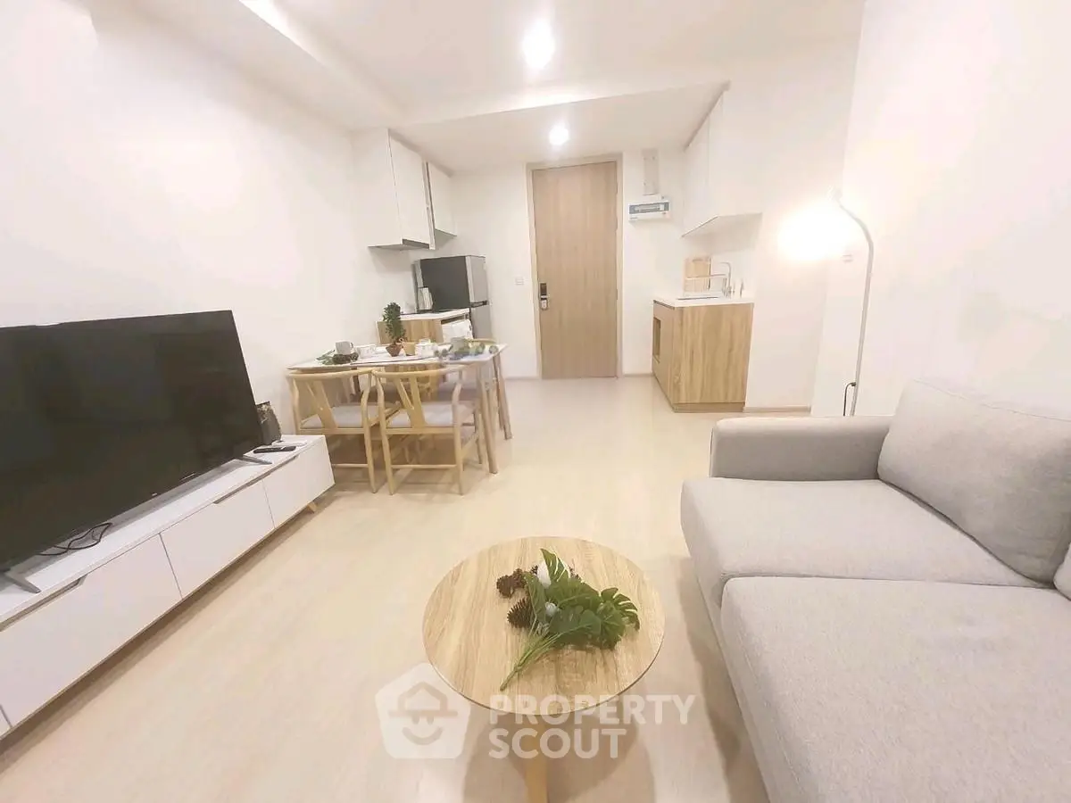 Modern living room with open kitchen, stylish furniture, and cozy ambiance.