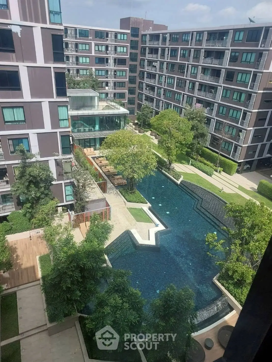 Modern apartment complex with lush garden and inviting swimming pool view.