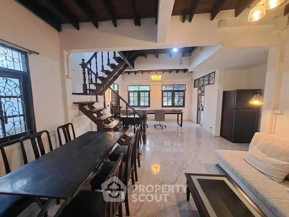 Spacious living room with elegant staircase and modern furnishings in a stylish home.