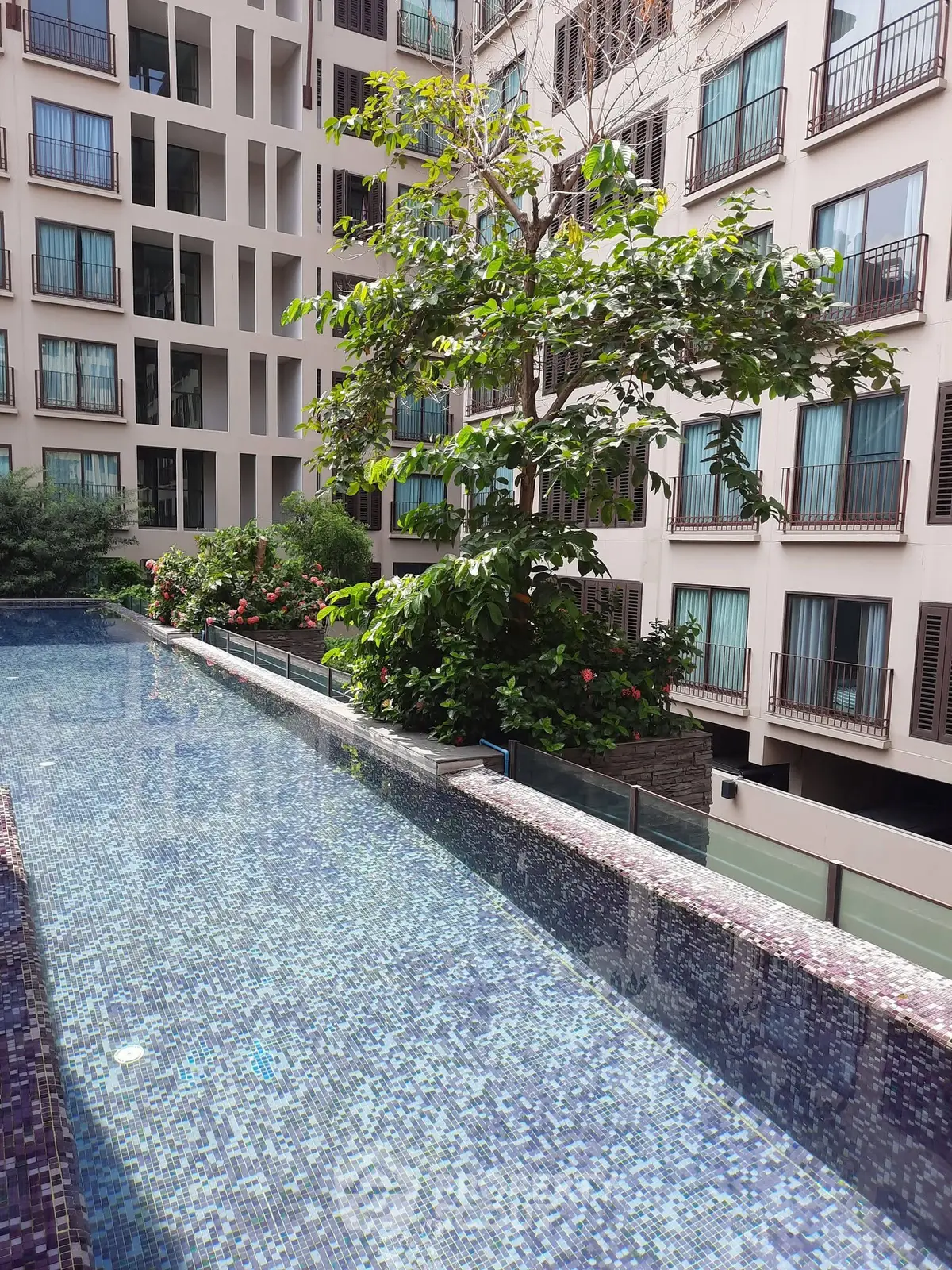 Luxurious apartment complex with stunning poolside view and lush greenery.
