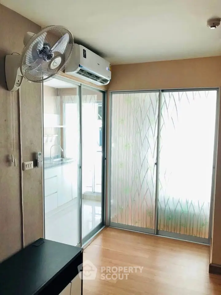 Modern room with sliding glass doors and air conditioning, featuring a wall-mounted fan and wooden flooring.