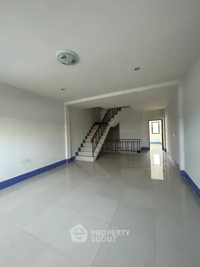 Spacious interior with modern staircase and tiled flooring, ideal for customization.