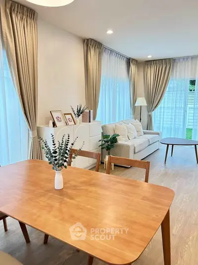 Elegant living room with natural light, cozy sofa, and stylish dining area in modern home.