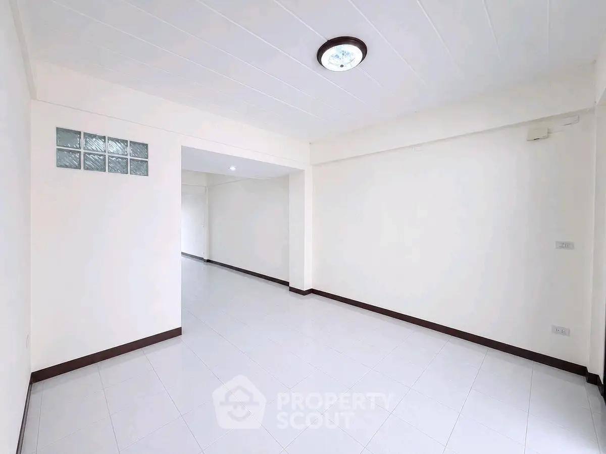 Spacious empty living room with white walls and tiled floor, ready for customization.