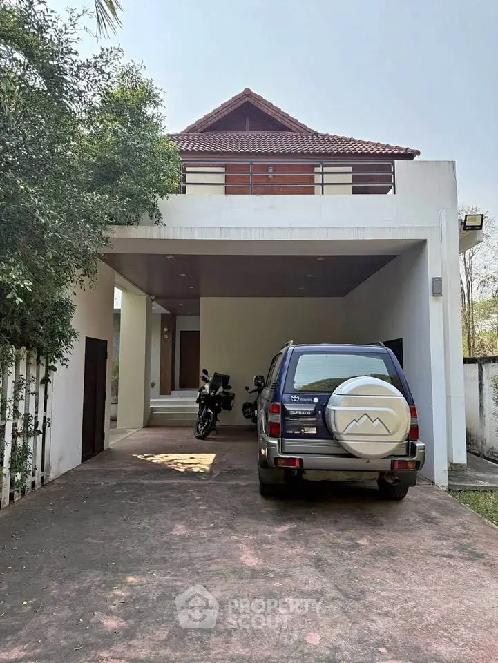 Modern two-story house with carport and driveway, featuring a sleek exterior design and spacious parking area.