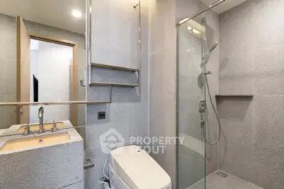 Modern bathroom with sleek design, featuring a glass shower enclosure and contemporary fixtures.