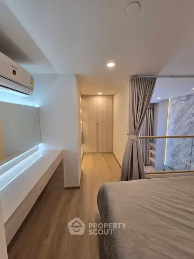 Modern bedroom with sleek design and wooden flooring, featuring a cozy bed and stylish lighting.