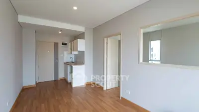 Modern minimalist apartment interior with wooden flooring and open kitchen layout.