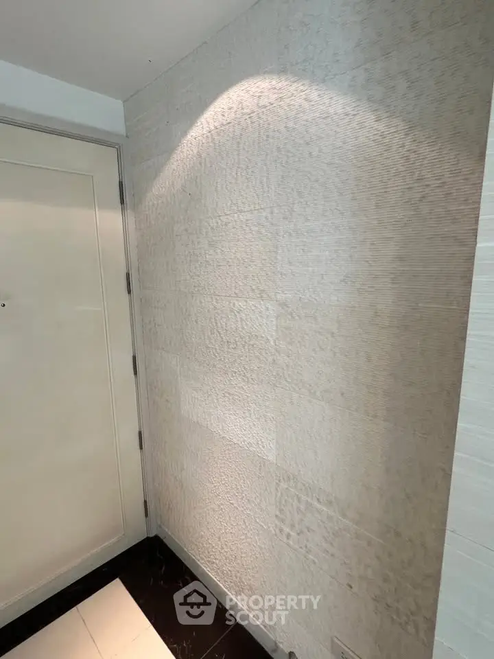 Elegant hallway with textured walls and modern lighting in a luxury apartment building.