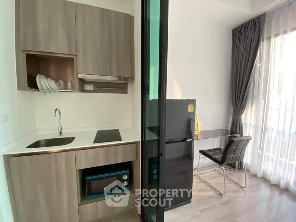 Modern compact kitchen with sleek appliances and dining area in bright apartment