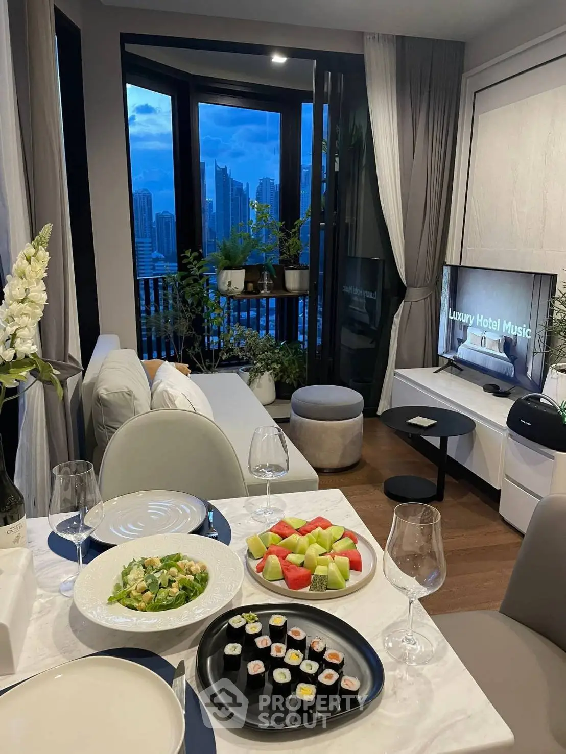 Stylish living room with city view, elegant decor, and dining setup, perfect for urban living.