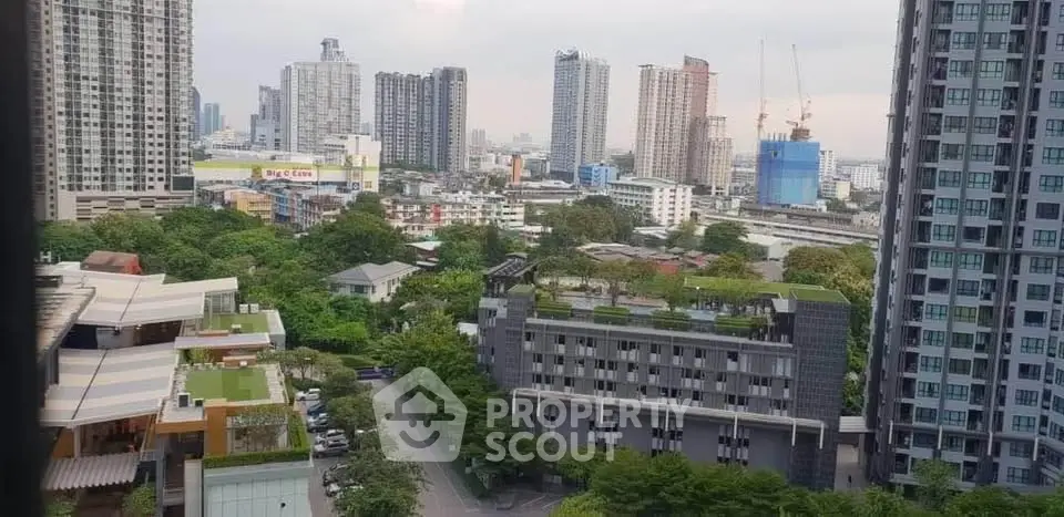 Stunning cityscape view from high-rise apartment with lush greenery and modern buildings.