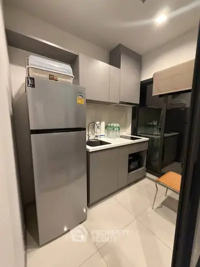 Modern compact kitchen with sleek cabinetry and stainless steel appliances in a stylish apartment.