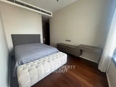 Modern bedroom with sleek design and wooden flooring, featuring a stylish bed and contemporary furniture.