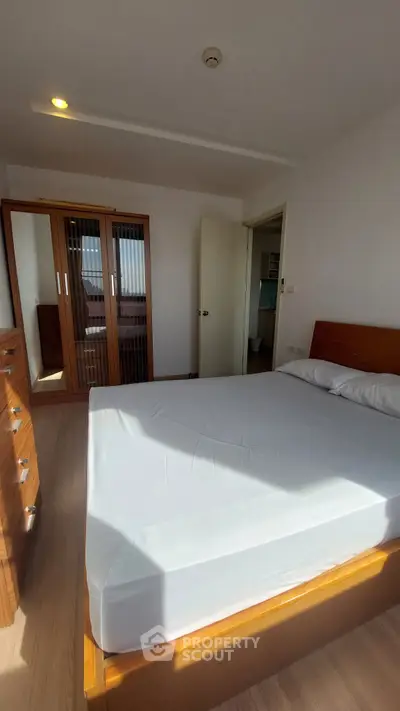 Bright bedroom with wooden furniture and large wardrobe, ideal for cozy living.