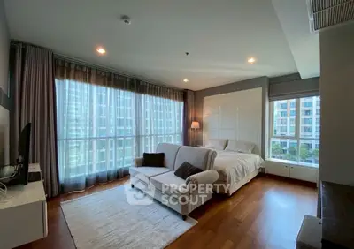 Spacious bedroom with large windows and cozy seating area in modern apartment